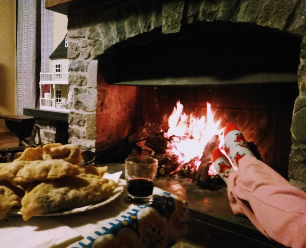 Cozy winter evening in Cilento Italy with a roaring fireplace, traditional Italian panzerotti, a glass of red wine, and warm holiday socks.